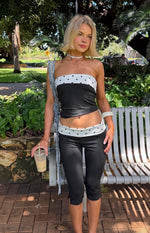 Fitted black capris with a white polka dot band at the waist and small side slits at the mid-calf hem
