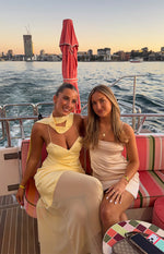 Yellow satin maxi dress with a draped scarf neckline, deep V-neck, thin spaghetti straps, and sheer overlay skirt
