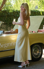 Side view of a light yellow strapless maxi dress with a cut-out back and a horizontal band