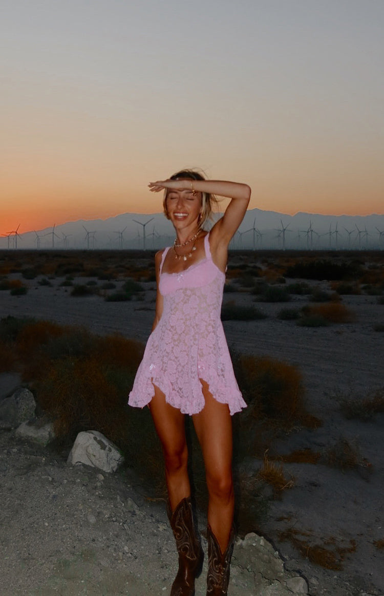 Flowy pink lace mini dress with a square neckline, thin straps, and an asymmetrical ruffled hem