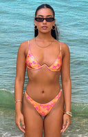 Girl wearing orange floral bikini top and white micro mini shorts with black sunglasses