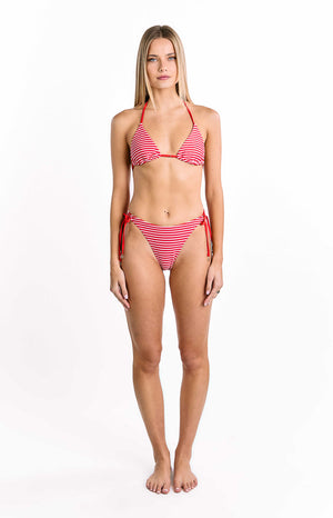 Our model wears bikini bottoms featuring thin horizontal stripes in bright red and white. The bottom is a minimal low-rise style with a V-shaped front and adjustable red string tie closures at the hips each finished with a small metallic accent.
