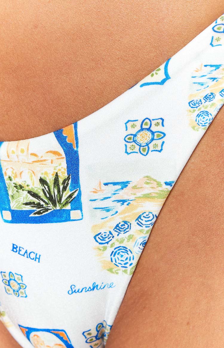 Close-up of the white bikini bottoms with blue and yellow Italian print, featuring landscape, tile motifs, and 'BEACH' text