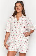 Side view of white cherry print pajama shorts and matching collared short sleeve button-up top