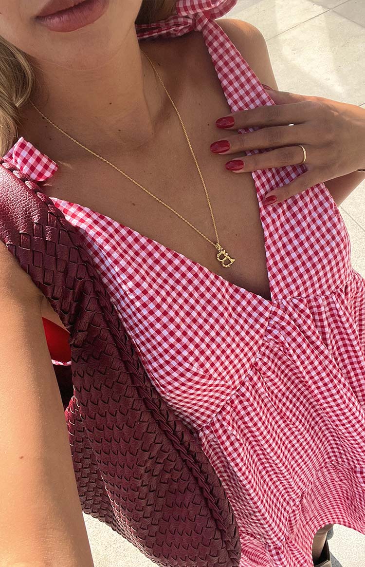 Close-up of the red gingham mini dress showing the deep V-neckline and tied halter strap