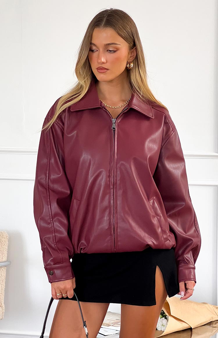 Front view of a relaxed fit burgundy PU bomber jacket with a pointed collar, full zip front, and buttoned cuffs