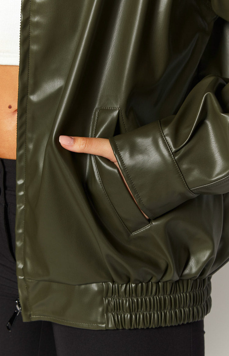 Close-up of the olive PU bomber jacket showing the side pocket, wide cuff, and ribbed elastic hem