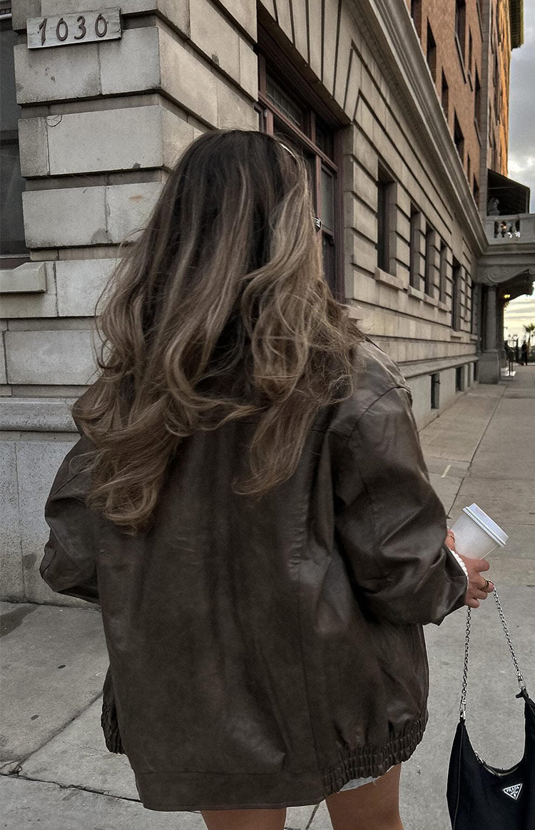 Rear view of a vintage brown PU bomber jacket with a relaxed fit and elasticated hem