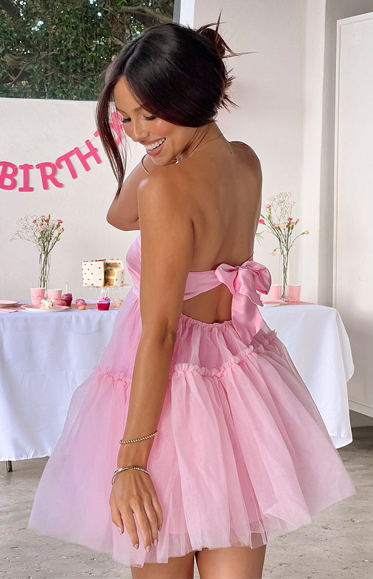 Rear view of a pink strapless mini dress with a large back bow and tiered ruffled tulle skirt