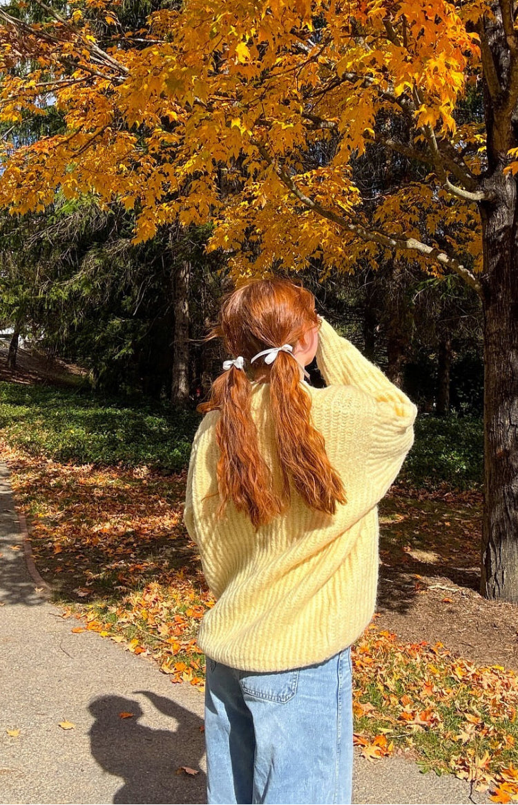 Rear view of a yellow oversized sweater with a chunky ribbed knit texture and relaxed long sleeves