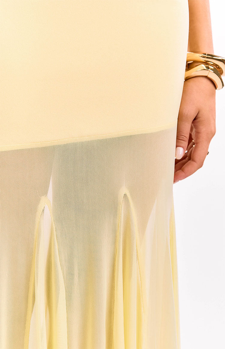 Close-up of the sheer yellow mesh overlay of the maxi dress skirt with a solid lining and draped hem detail