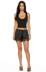 Black satin shorts with a relaxed fit, elasticated waist, and delicate black lace hem