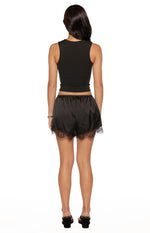 Rear view of black satin shorts with a wide elasticated waist and delicate lace trim along the hem