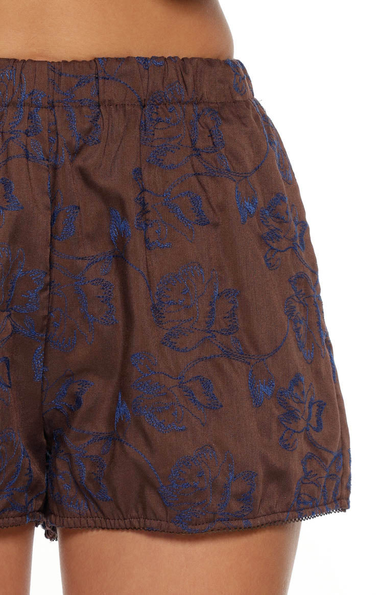 Close-up of the brown shorts with blue floral embroidery, elasticated waistband and gathered hem