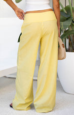 Rear view of yellow wide-leg pants with a wide flat waistband and flowy fit
