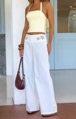 Front view of white wide-leg pants with intricate floral cutouts on the high waistband