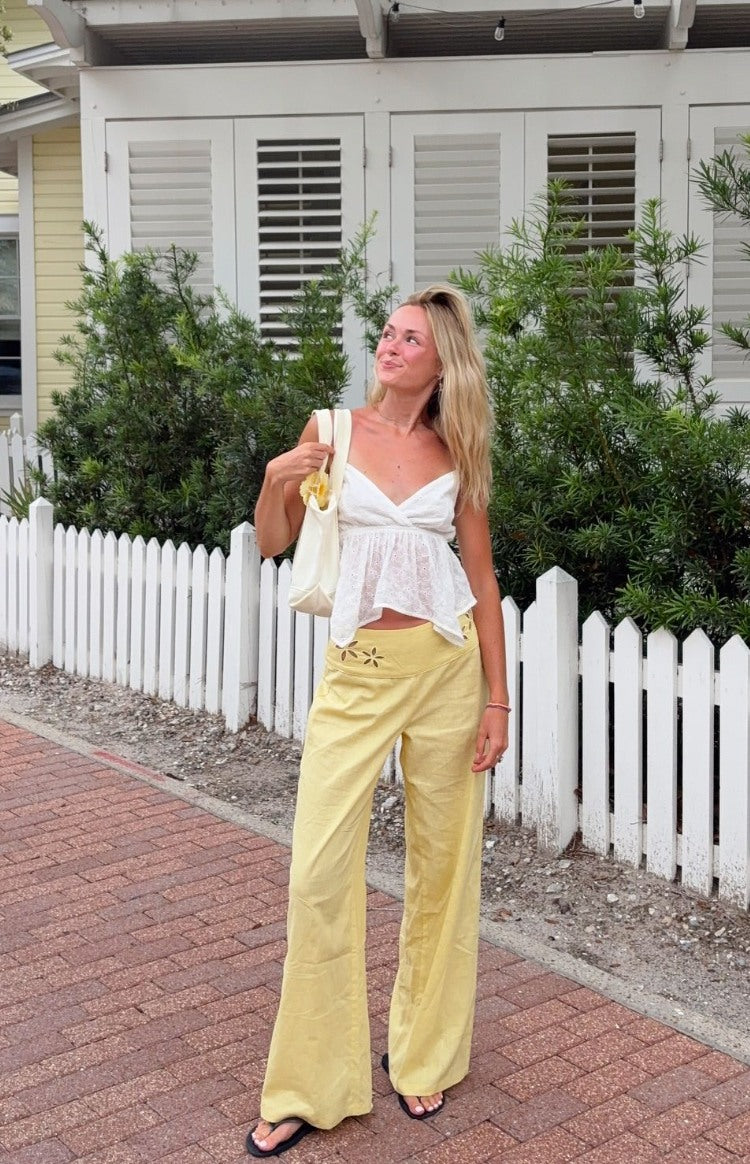 Yellow wide leg pants with floral cutouts on the hips and a relaxed, flowy fit