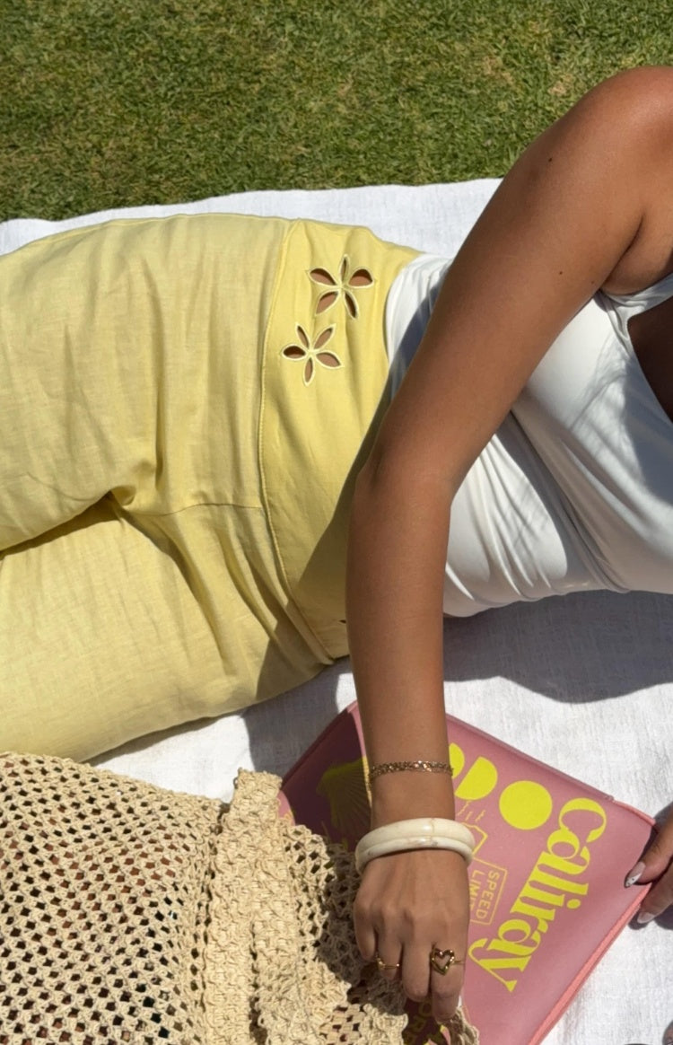 Close-up of the floral cut-out details on the side of yellow wide-leg pants