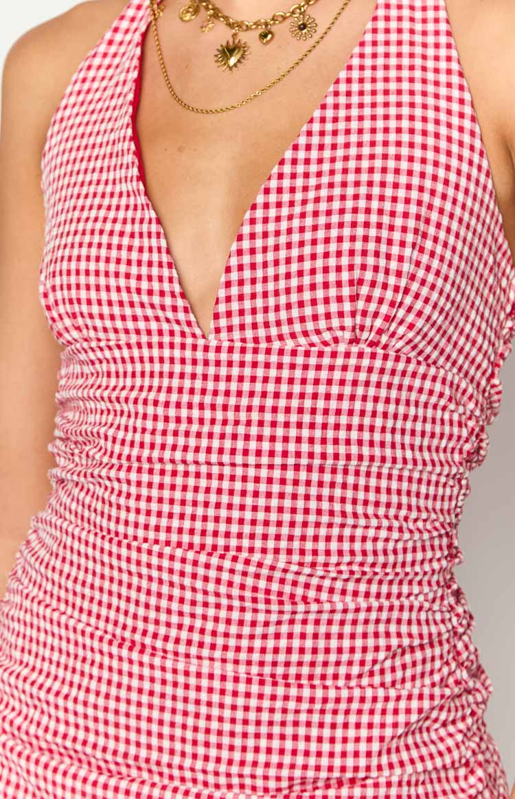 Close-up of the deep V-neck and ruched bodice of a red and white gingham halter mini dress