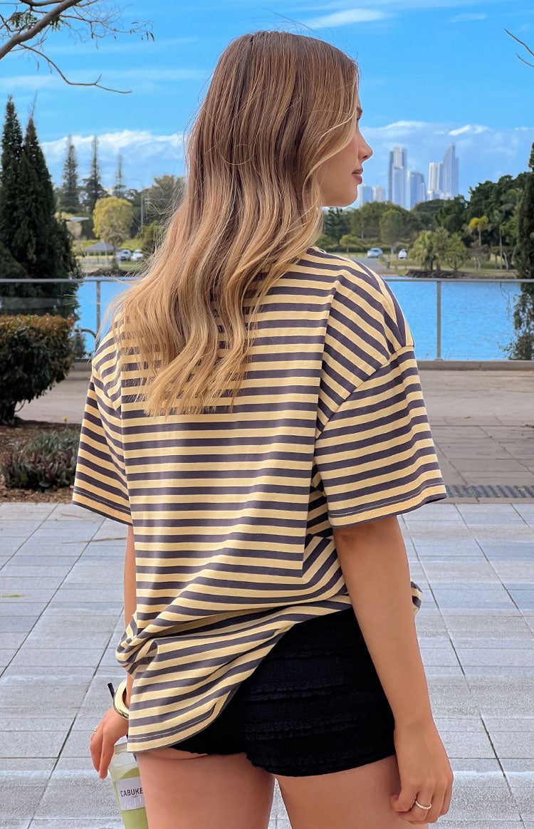 Rear and side view of the yellow and grey striped oversized tee, showing its relaxed fit and dropped short sleeves