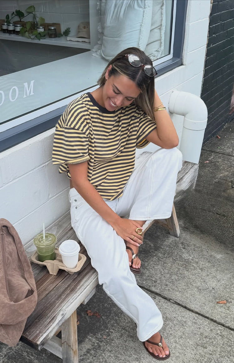 Side view of a relaxed fit yellow and black striped oversized tee with a black trim round neck and short sleeves