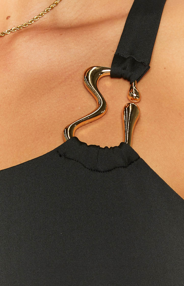 Close-up of the gold-toned sculptural hardware detail connecting the strap to the black mini dress