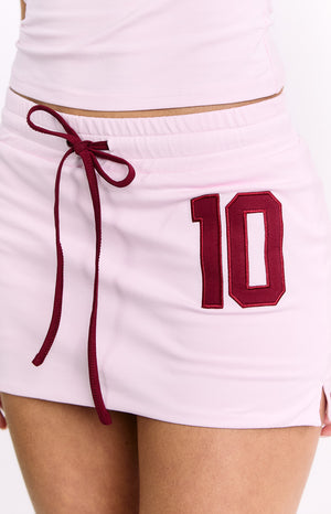 Close-up of the pink jersey skort showing the elasticated waist with burgundy drawstring and embroidered number 10