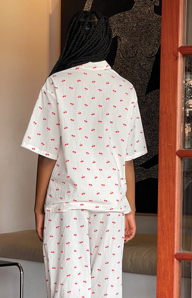 Rear view of a white short-sleeve pajama shirt with an all-over red cherry print