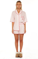Model wears the Alexea Pink Stripe Pajama shorts featuring red contrast piping details. These shorts perfect for a comfortable and sweet summer sleepwear set.