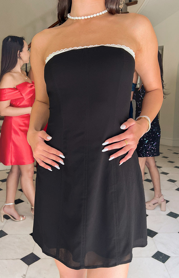 Black strapless mini dress with white lace trim along the neckline and vertical bodice seams