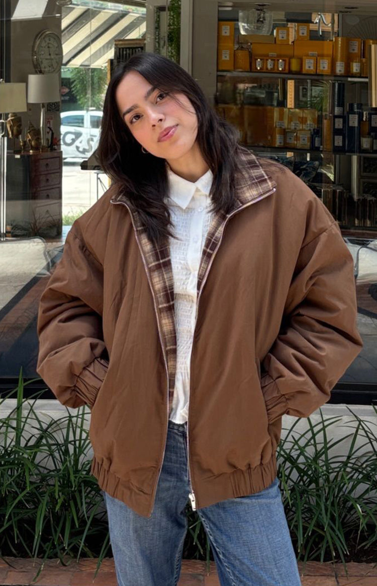 Front view of a brown puffer jacket with a plaid lining visible at the collar and a partially open zipper
