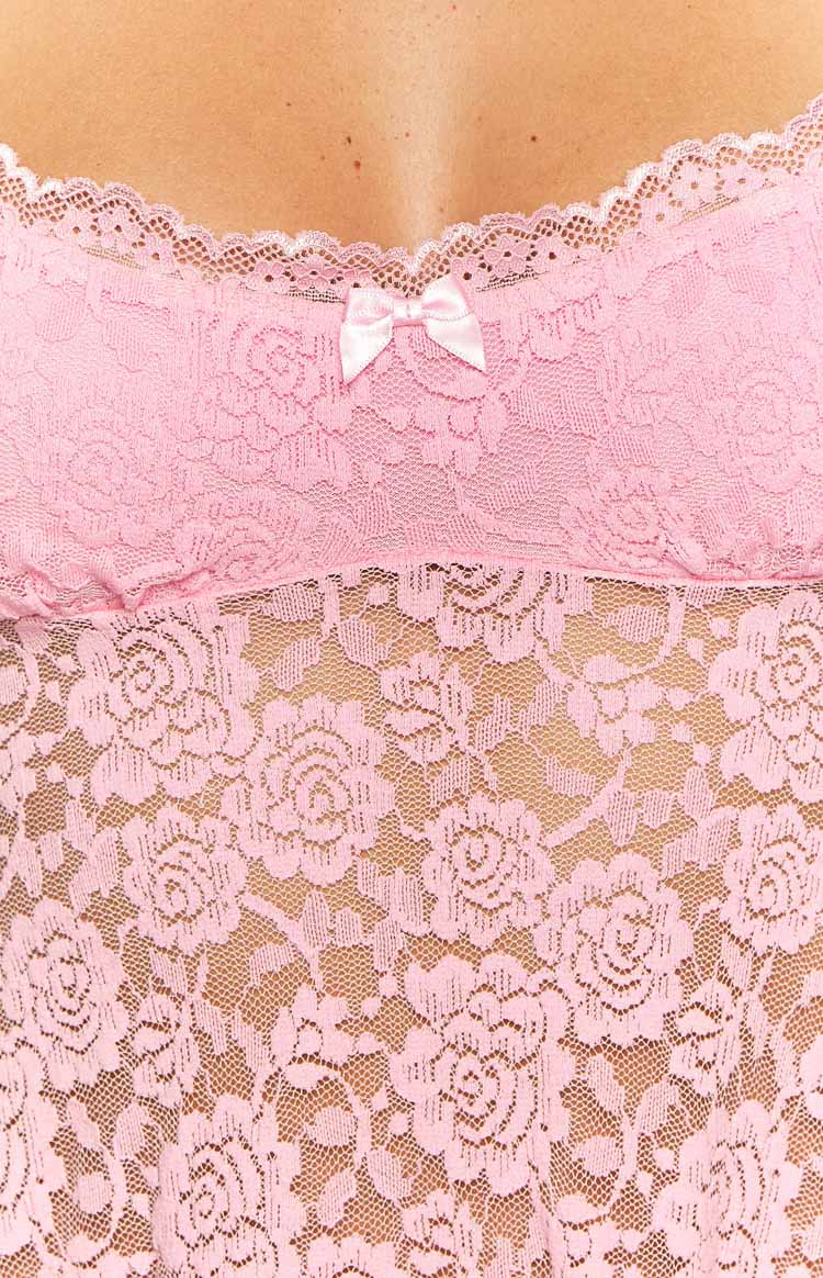 Close-up of the pink floral lace fabric, white scalloped trim, and small pink satin bow on the mini dress