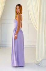 Side profile of a lilac crepe maxi dress with a structured bustier bodice, thin spaghetti straps, and a flowing skirt