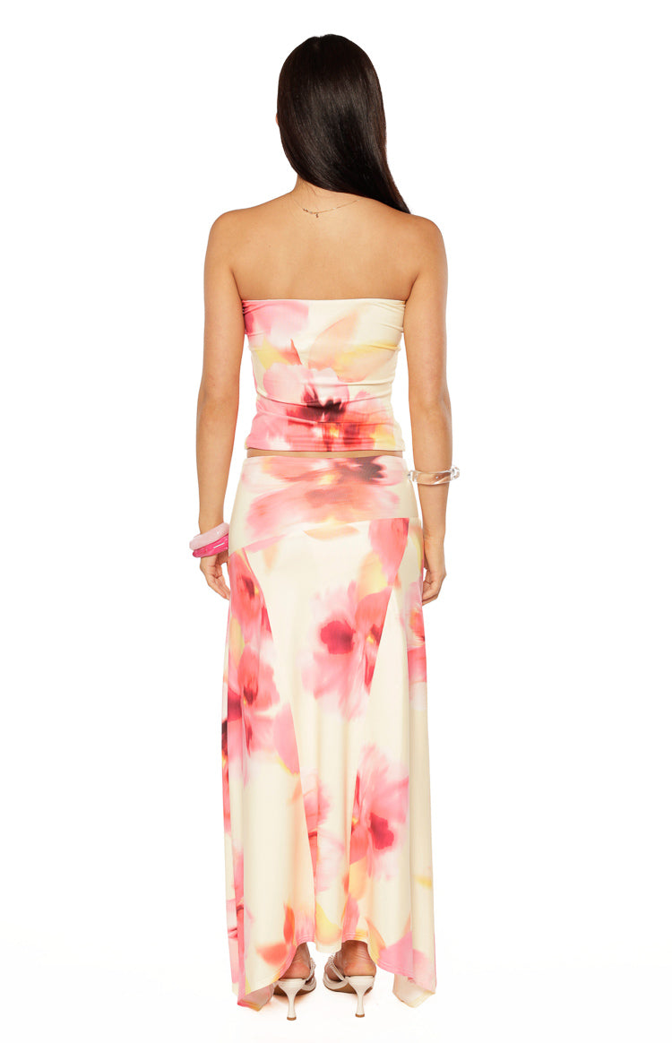 Rear view of a yellow and pink floral print maxi skirt with a hanky hem and flowy silhouette