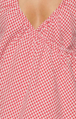 Close-up of the red and white gingham V-neckline with ruched bodice detail on the mini dress