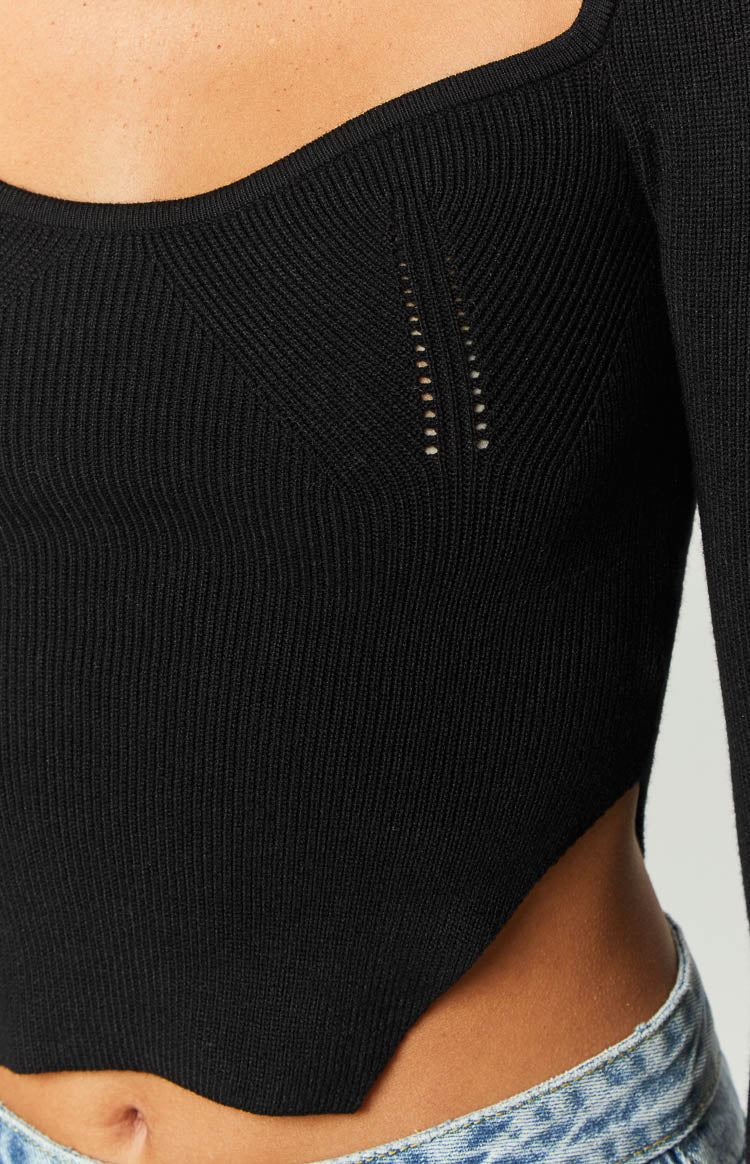 Close-up of black ribbed knit top with square neckline, perforated chest detail, and asymmetrical hemline