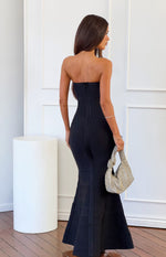 Rear view of a black strapless bandage maxi dress with an exposed back zipper and a mermaid-style flared hem