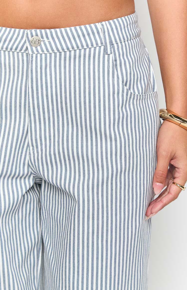 Close-up of the mid-rise waistband with a silver button and front pocket opening on navy and white striped jeans