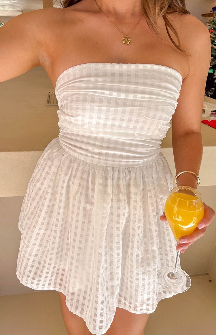 Close-up of the ruched strapless bodice and gathered skirt of a white checkered mini dress