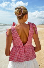 Rear view of a red gingham tie top with a deep V-back and tied shoulder straps, featuring a peplum hem