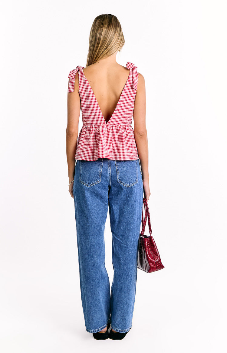 Rear view of a red gingham tie top featuring a deep V-back neckline, tie shoulder straps, and a peplum hem
