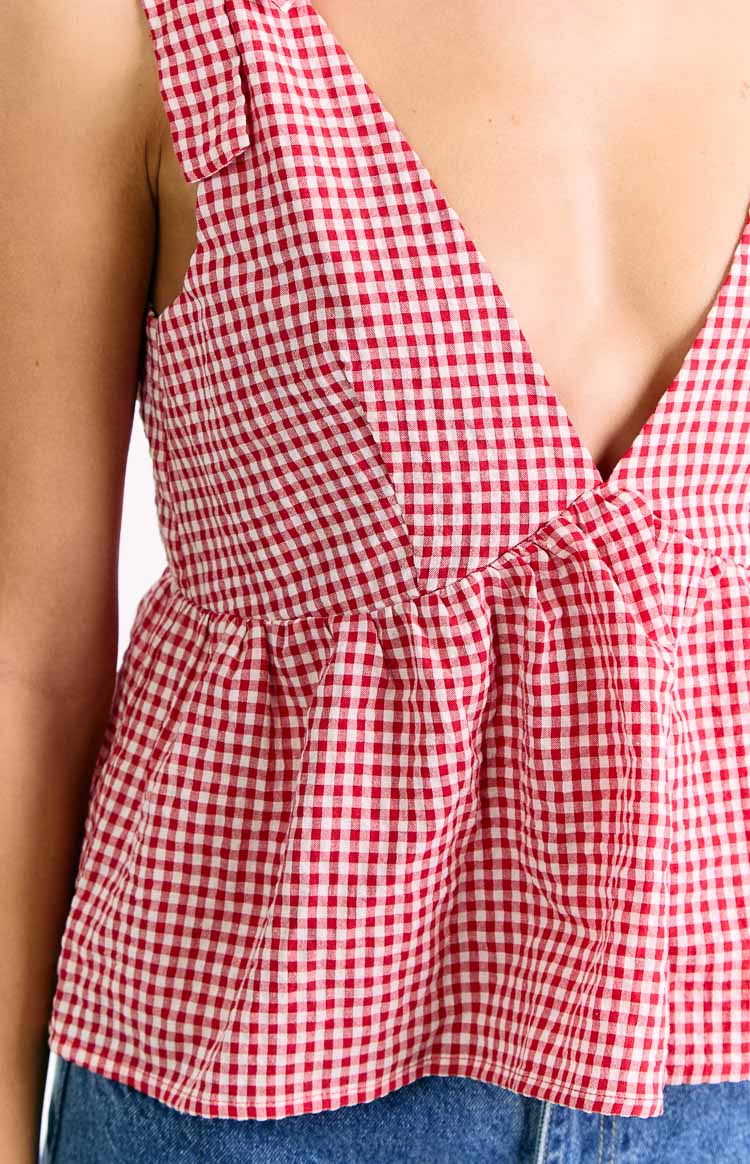 Red gingham tie top close-up showing the V-neck, gathered waist, and a tied shoulder strap