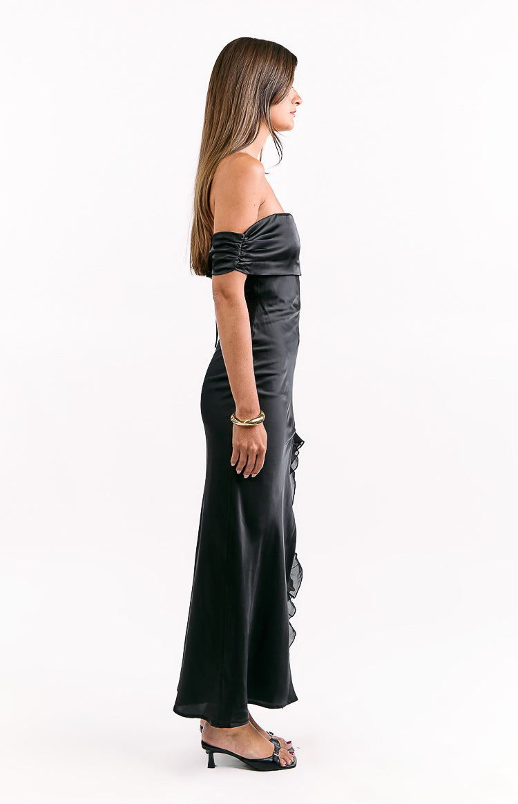 Side view of a black off-shoulder maxi dress with ruched sleeves and a ruffled side seam