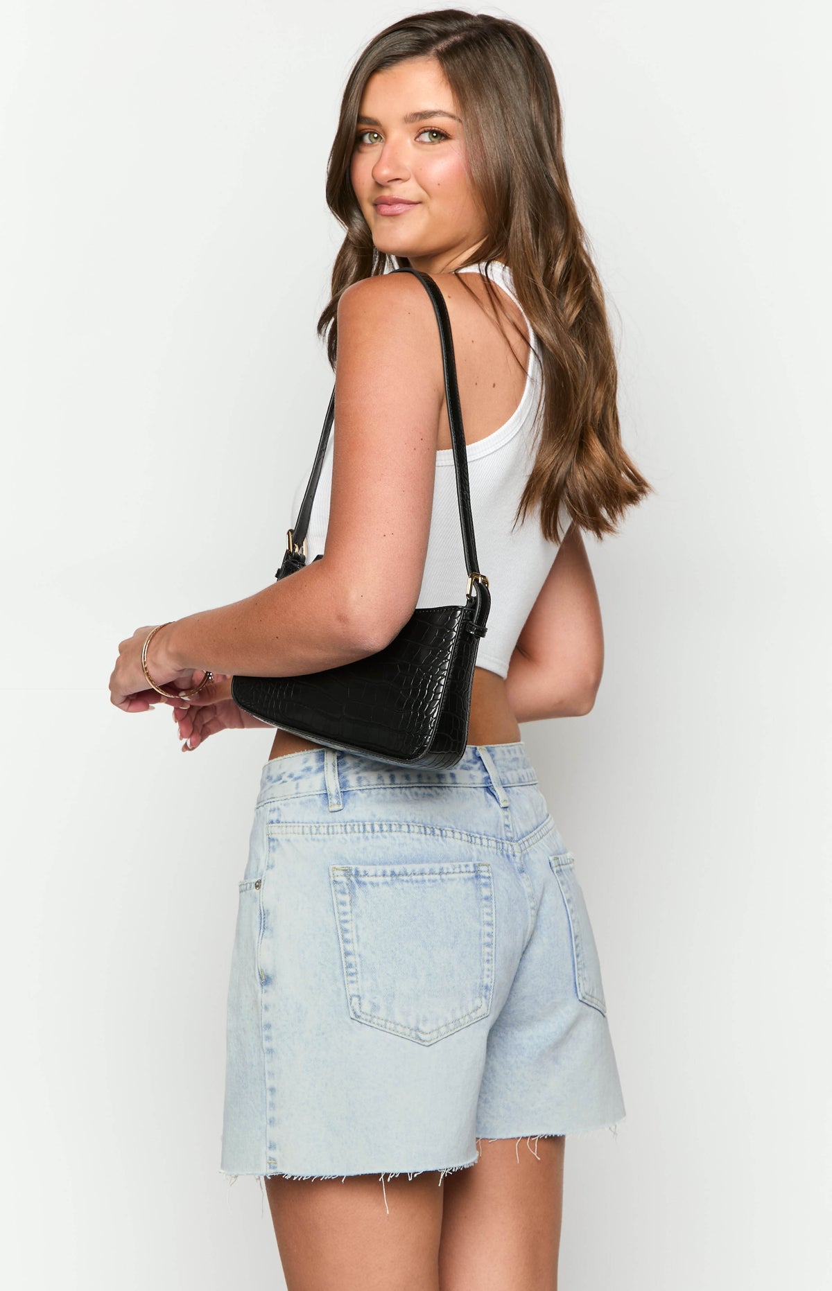 Rear view of light wash denim shorts showing the back pockets, waistband, and frayed raw hem