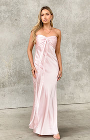 Pink satin strapless maxi dress with a gathered bust, central bow, and long flowing ties