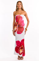 Girl posing with a drink and handbag in her hands. She is wearing a white strapless maxi dress with a pink orchid floral print design.
