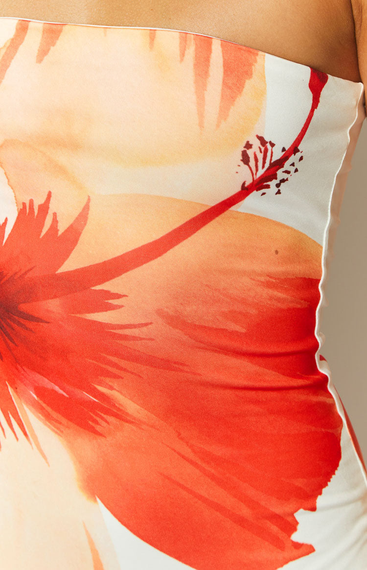 Close-up of the white maxi dress fabric, showing the large orange and red floral print and wavy lettuce hem