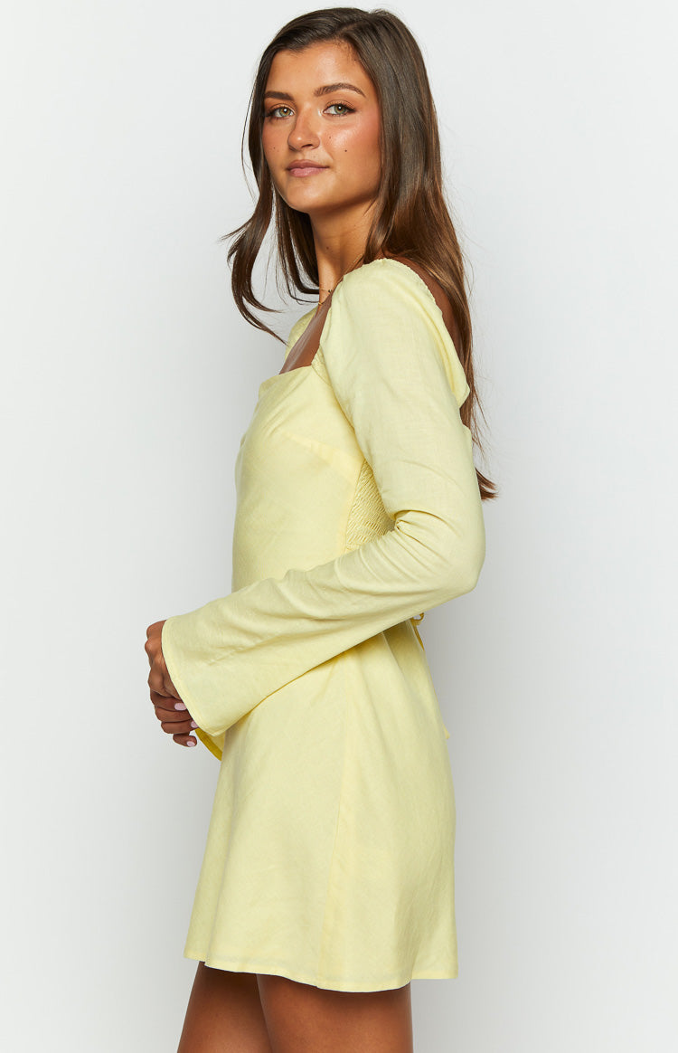 Side view of a yellow long sleeve mini dress showing the smocked back panel and flared cuffs