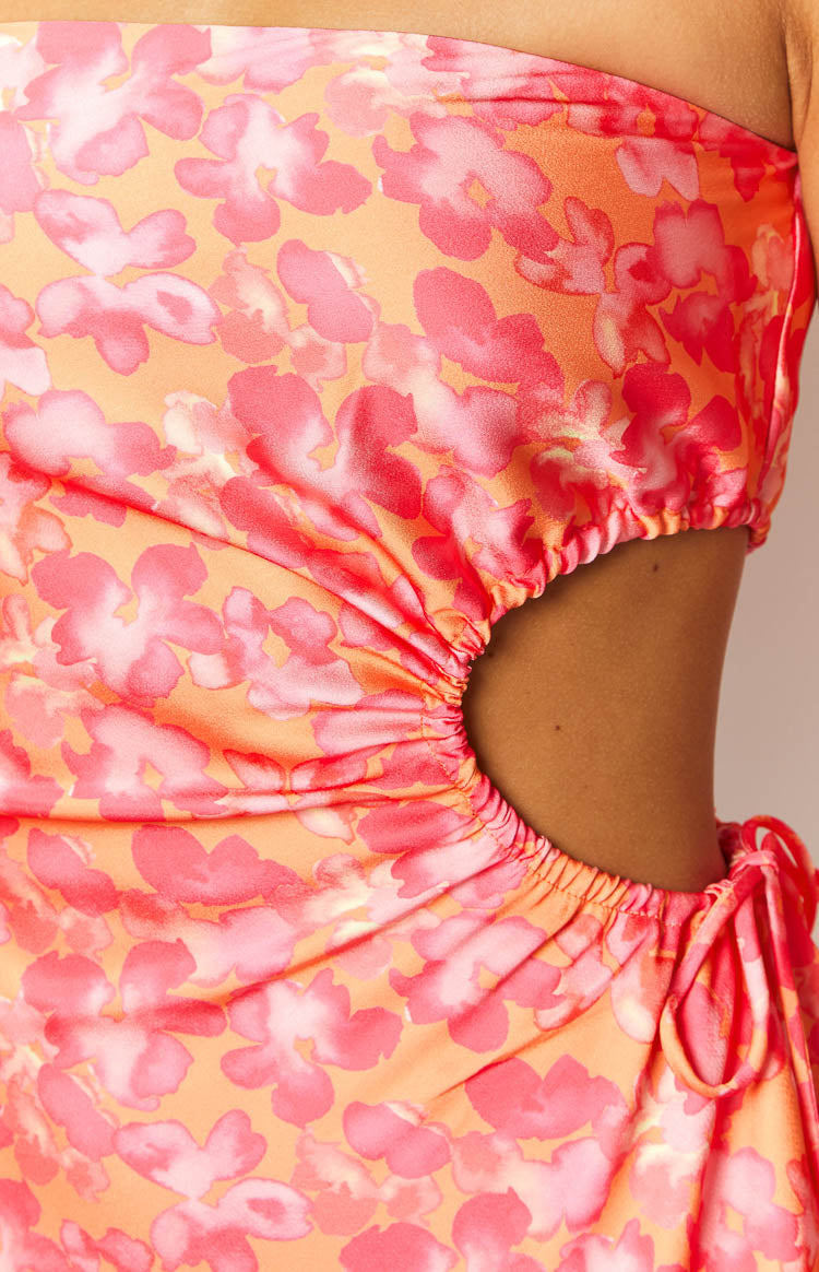 Close-up of the ruched side cutout on an orange floral mini dress showing the adjustable tie detail