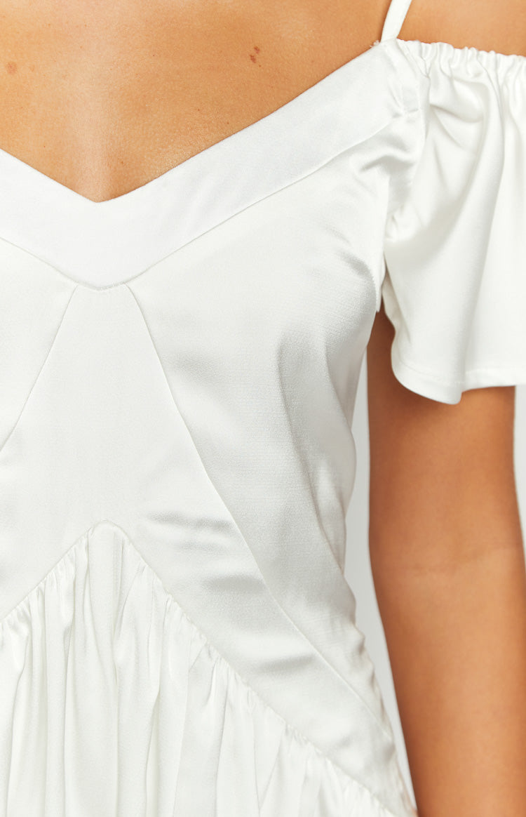 Close-up of the white satin V-neckline, off-shoulder ruffled sleeve, and bodice seaming of the playsuit